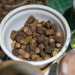 Il tavolo su cui Mino sta lavorando  anchesso pieno di attrezzi, pennelli, tappi di sughero, perline e tantissimi noccioli di olive